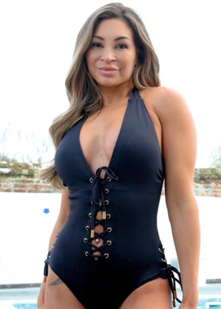 Love Island's AJ Bunker wearing a black swimsuit with lace-up details by a pool.