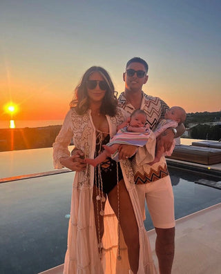 Amy Childs holding two babies by a pool with a sunset in the background