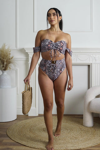 Woman wearing a leopard patterned bikini set in a room with a fireplace and decorative items.