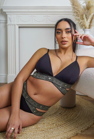 Woman wearing a black bikini with geometric patterns in a home setting
