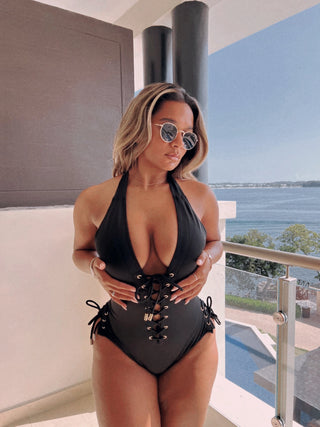 Woman in a black swimsuit standing on a balcony with ocean view
